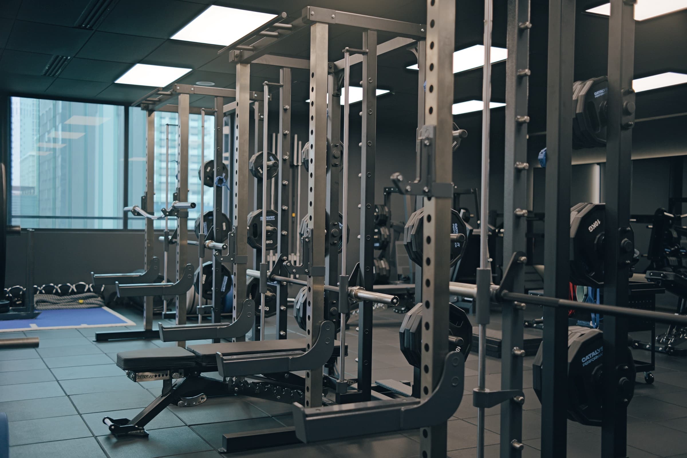 Catalyst Performance training floor, squat racks with city view through window, Singapore CBD