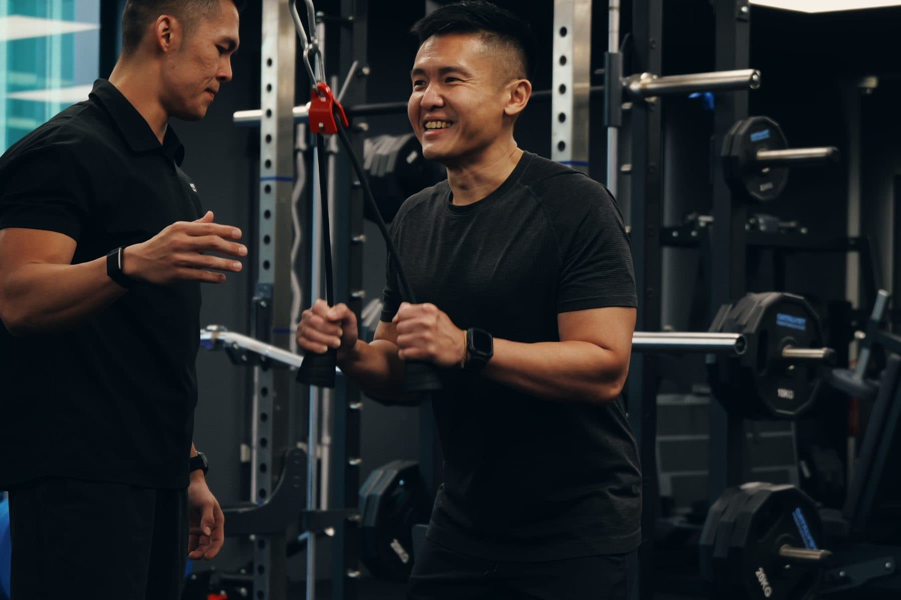 A Catalyst Performance member training a cable exercise with a coach cueing his form, private 1:1 personal training in Singapore CBD