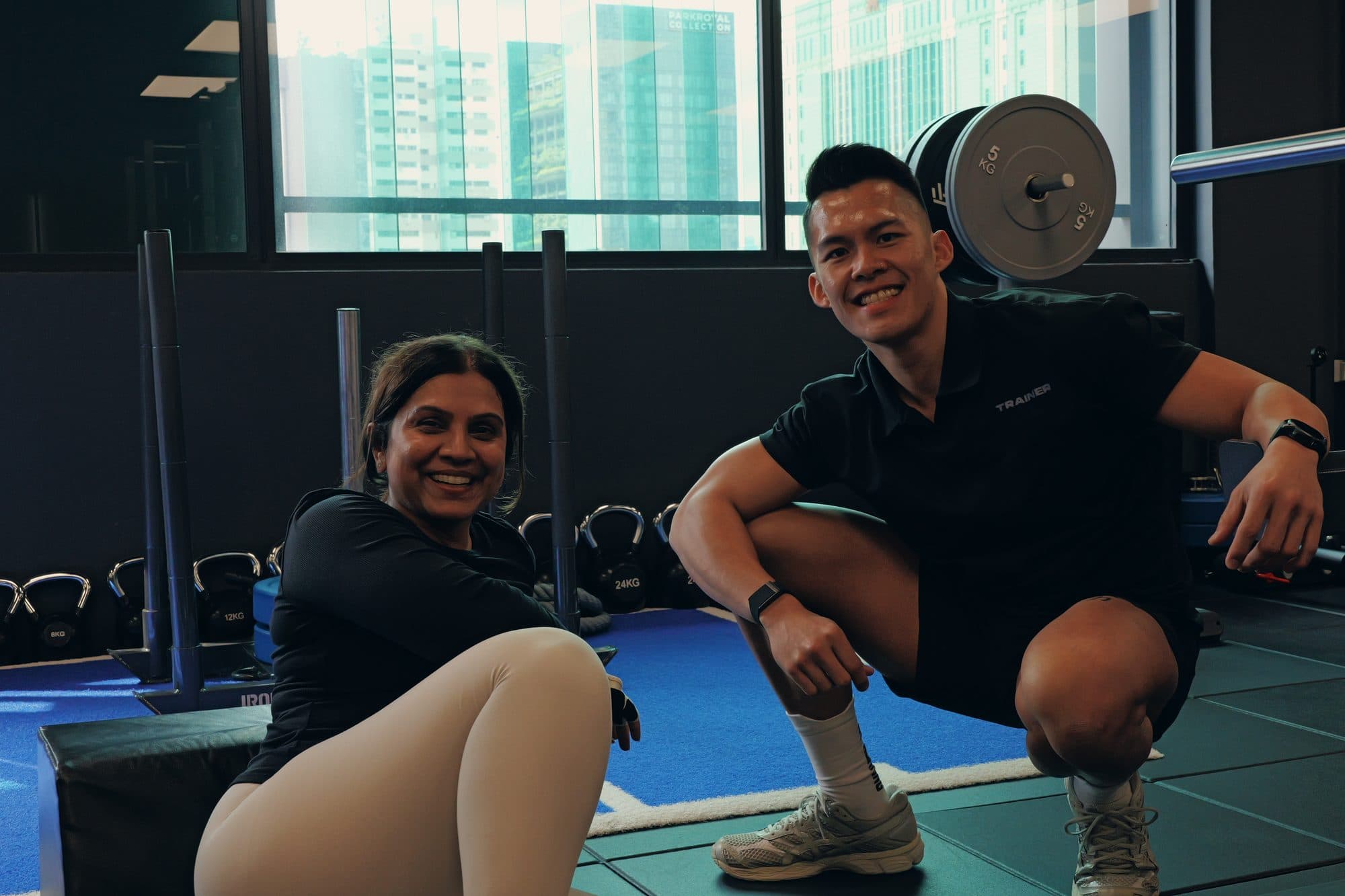 Catalyst Performance coach with a smiling South Asian female member at the rack, Singapore CBD personal training studio