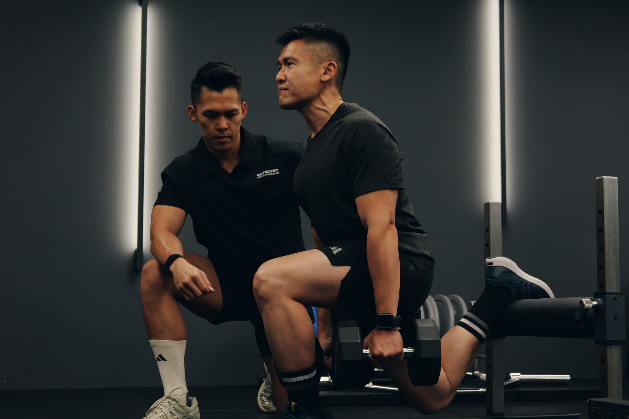 Catalyst Performance coach cueing a male member through a Bulgarian split squat, Singapore CBD personal training studio