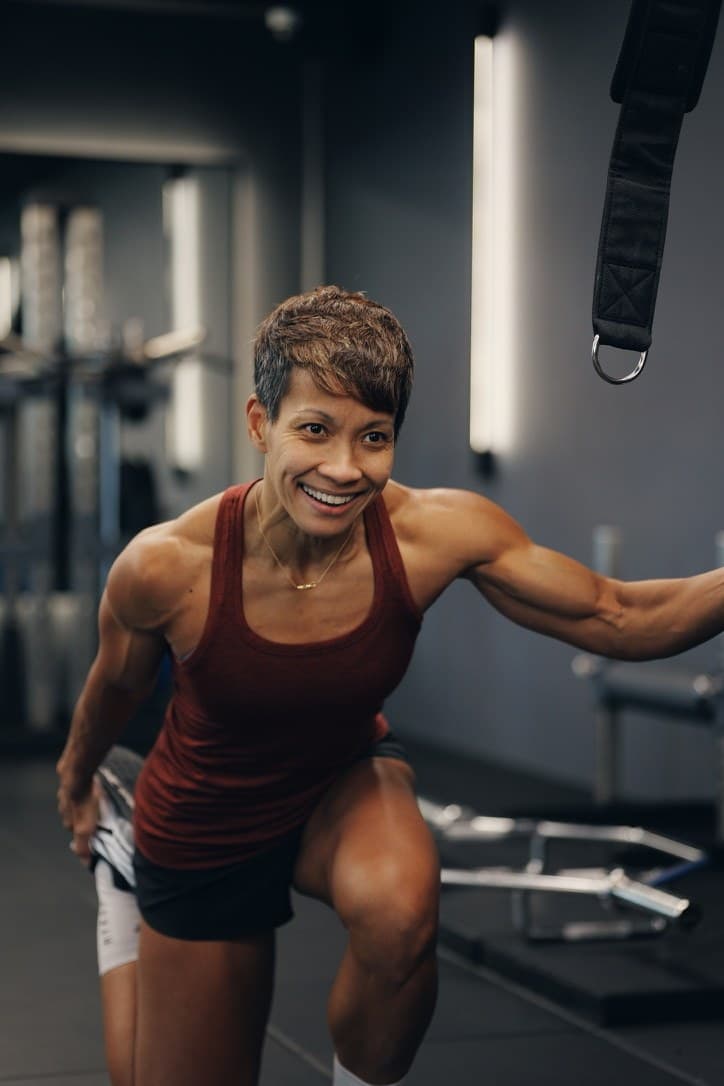 A strong, lean mature woman mid cable movement in the Catalyst Performance studio, Singapore CBD personal training