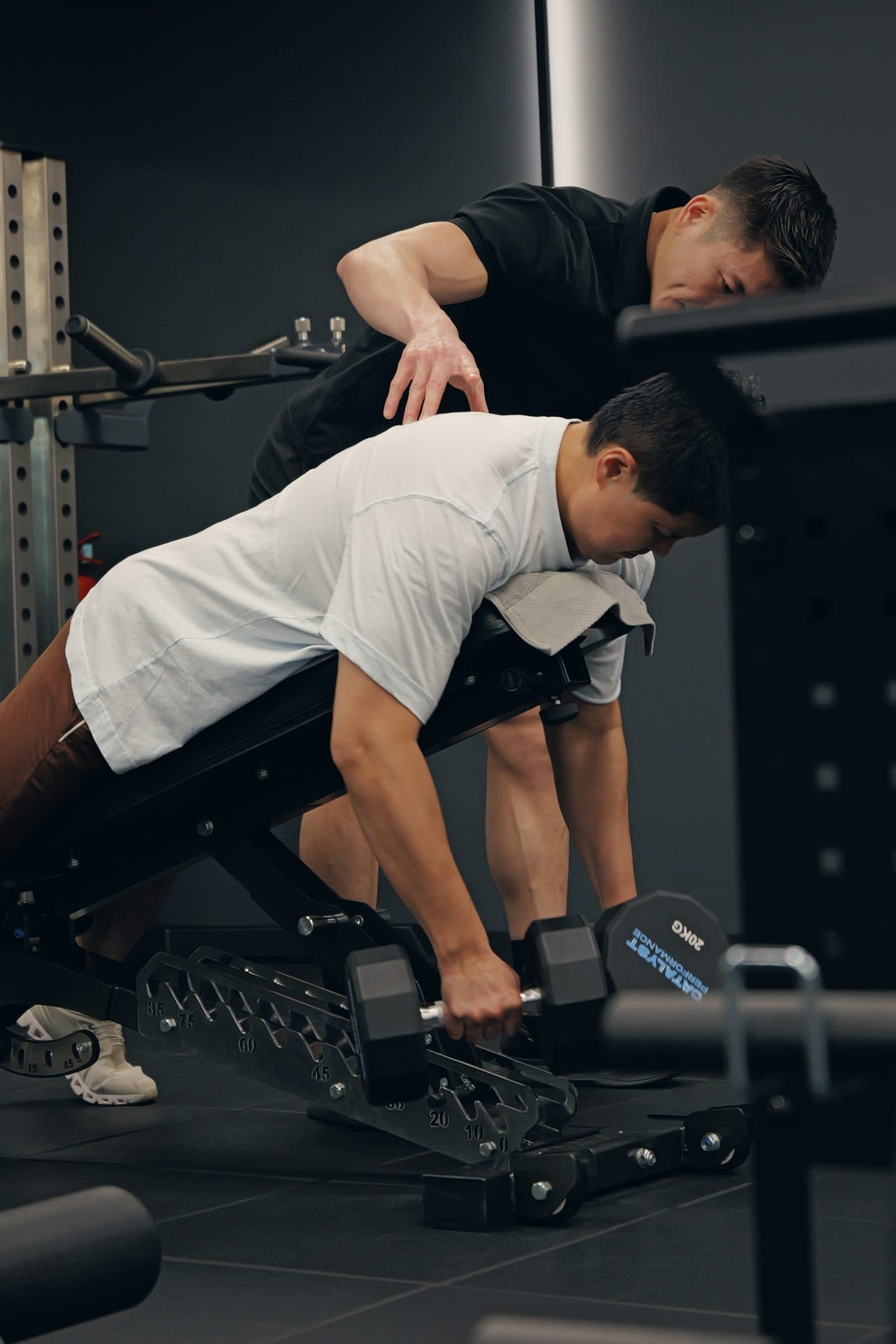 A Catalyst Performance coach spotting a client through a bench press in the Singapore CBD studio