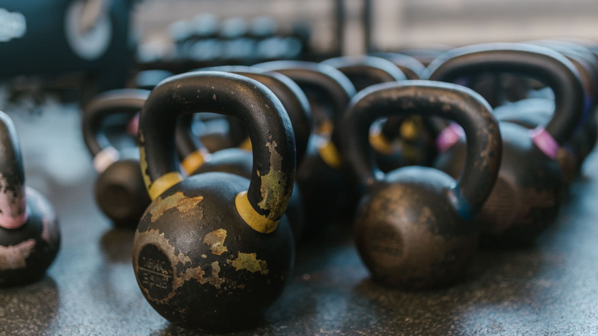 Black kettlebells arranged on a textured gym floor