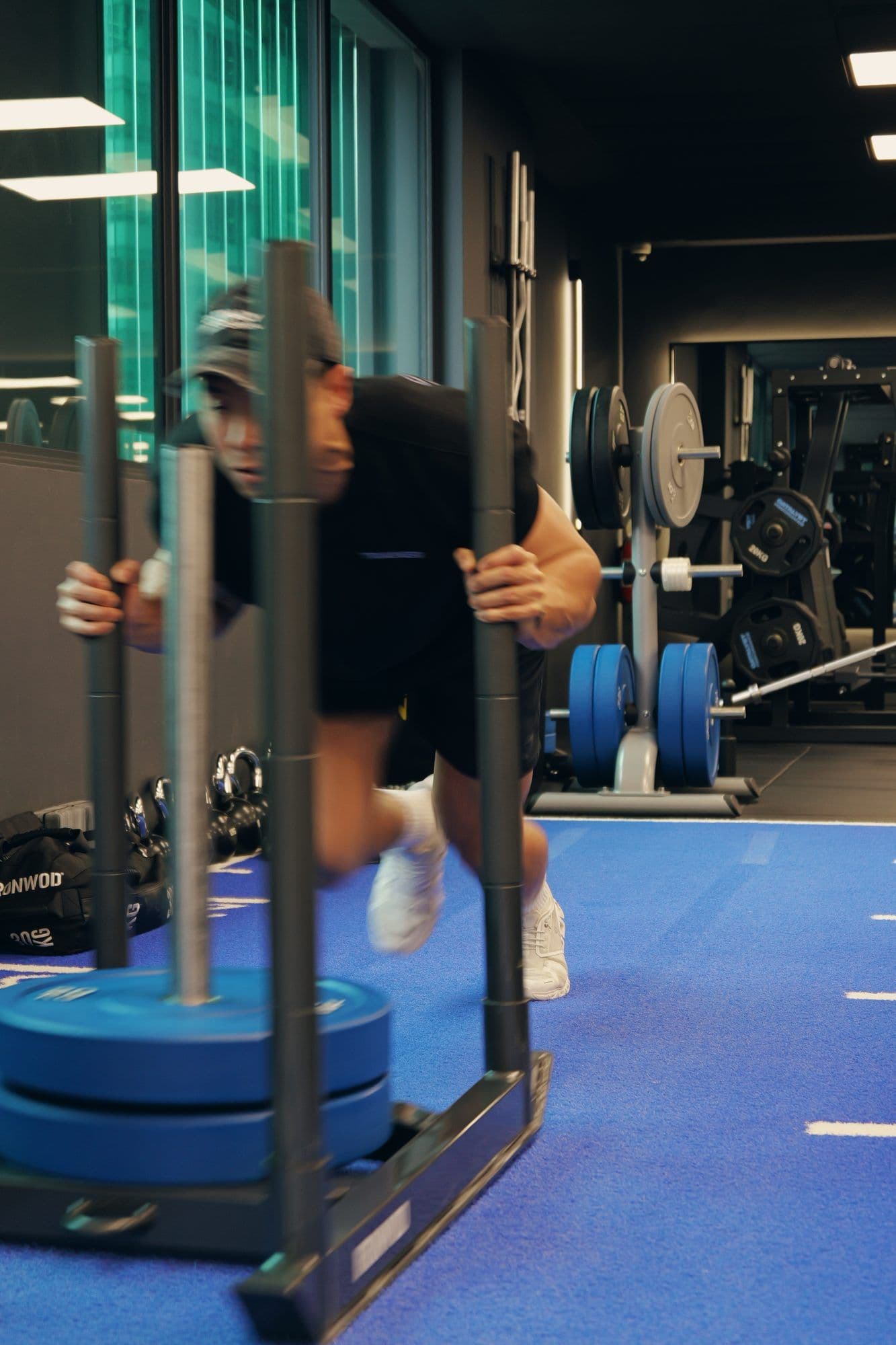 Athlete pushing a loaded sled on turf during HYROX-style training