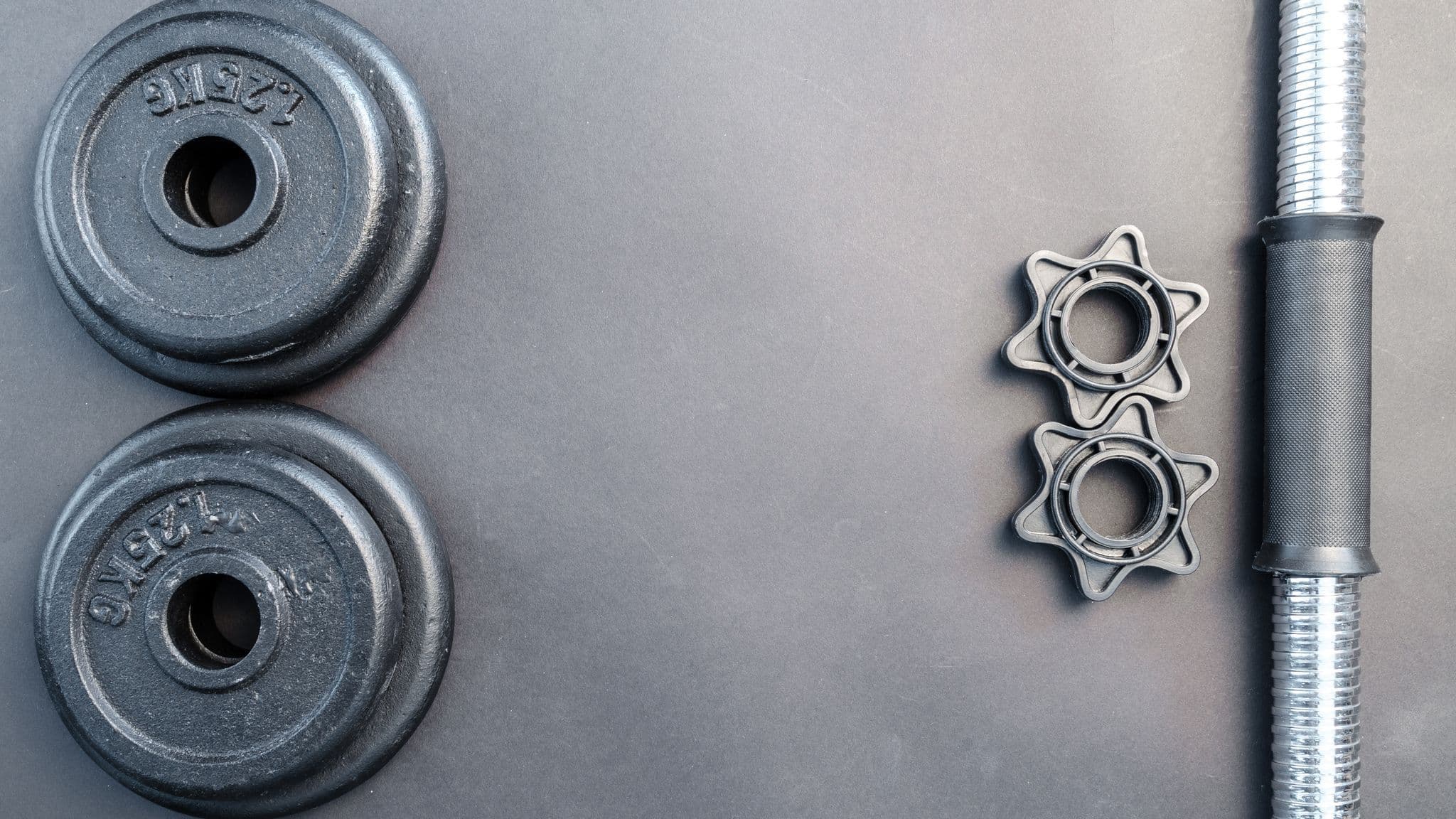A barbell and dumbbells arranged on a neutral surface