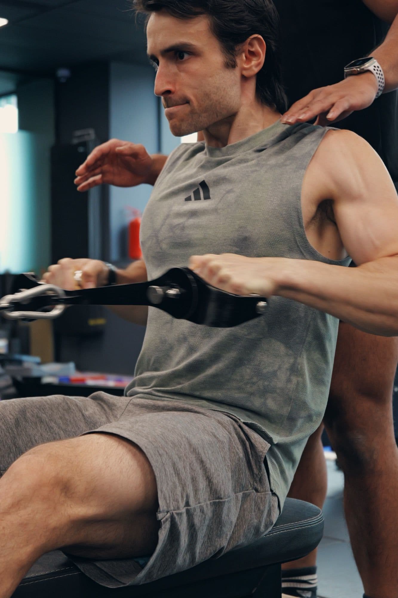 Coach giving hands-on cues during a seated row at a Singapore training studio