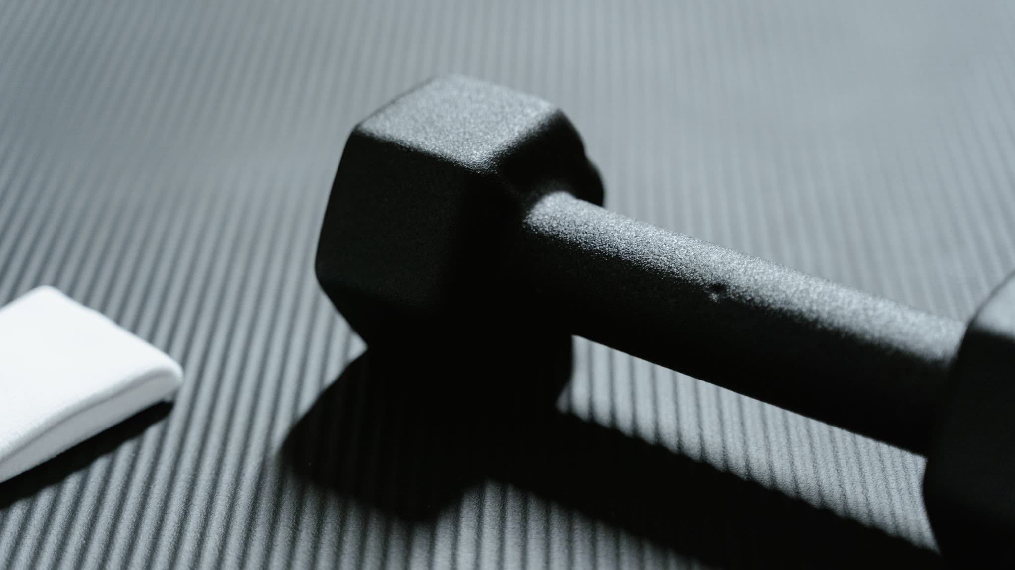 A single black dumbbell on a textured training mat