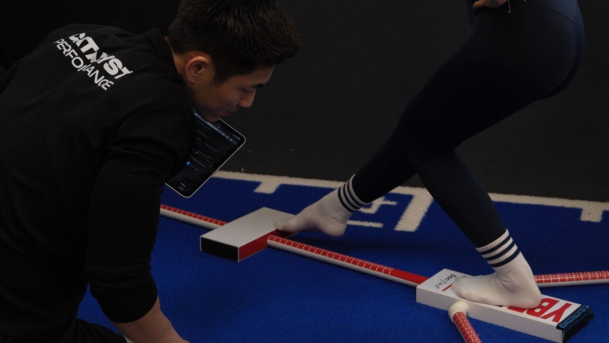 A Catalyst coach measuring a client's anterior reach on the Y-Balance Test apparatus in the studio