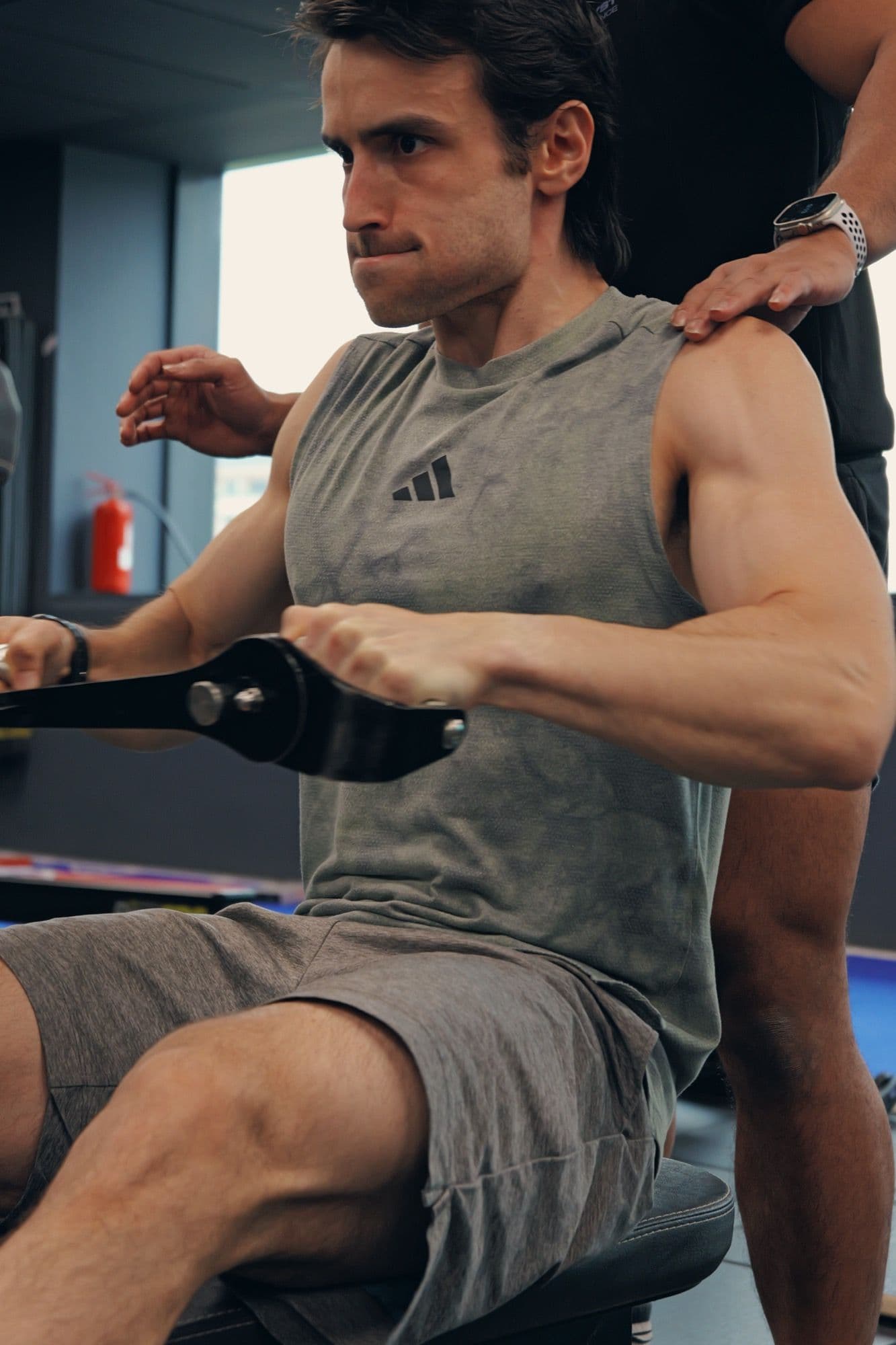 Coach guiding a supported row exercise with hands-on cues at a Singapore studio