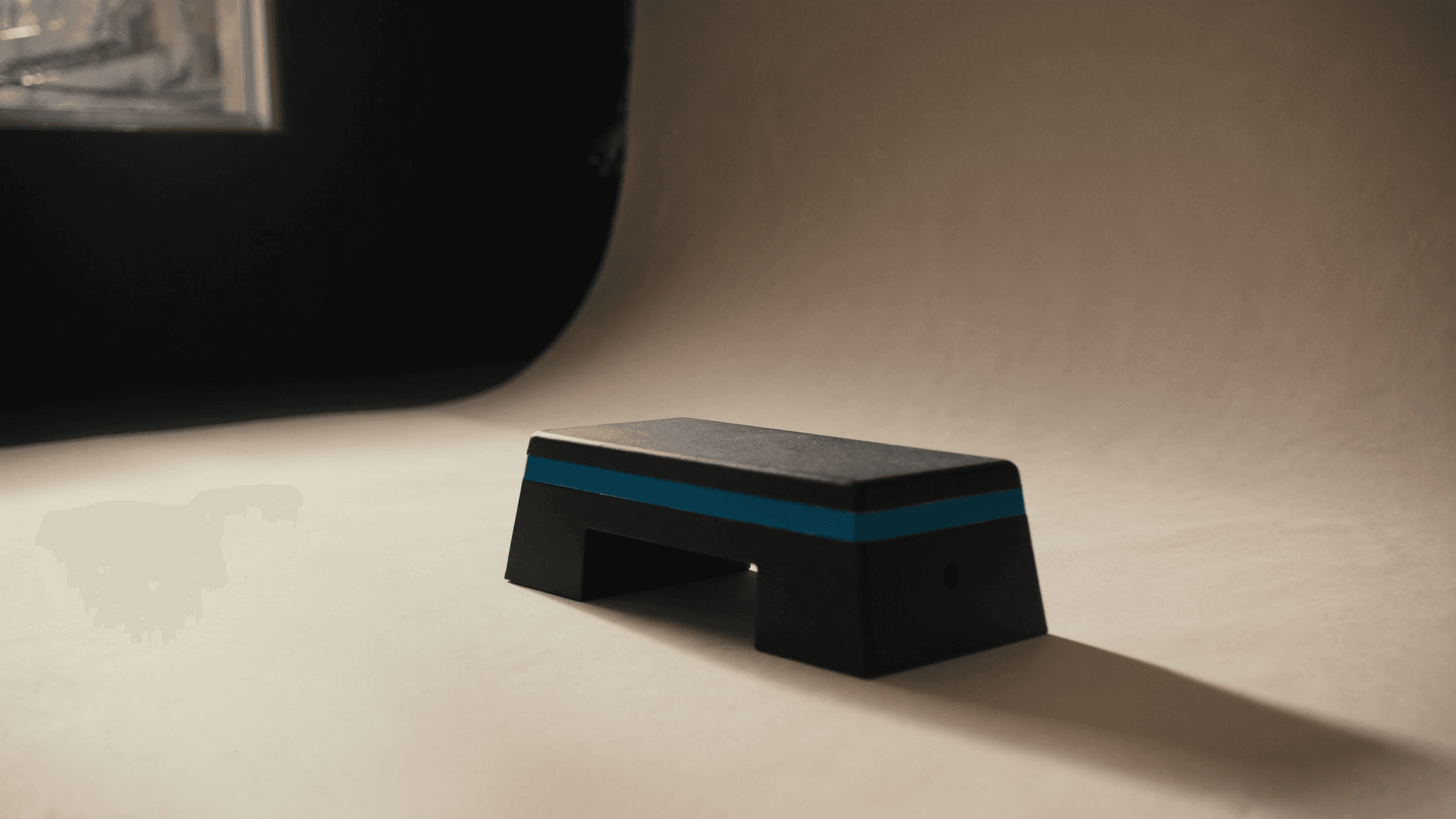 A step platform on a warm studio floor in soft window light, used for calf-raise loading