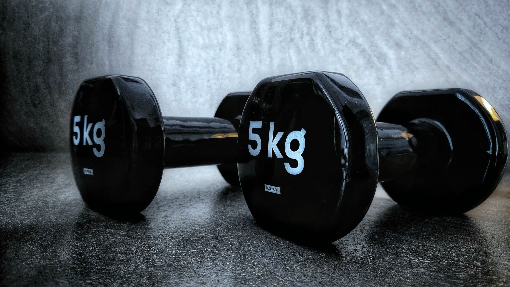 A loaded barbell on the rack inside the Catalyst Performance studio at Manulife Tower, lit low against a dark wall, no people in frame