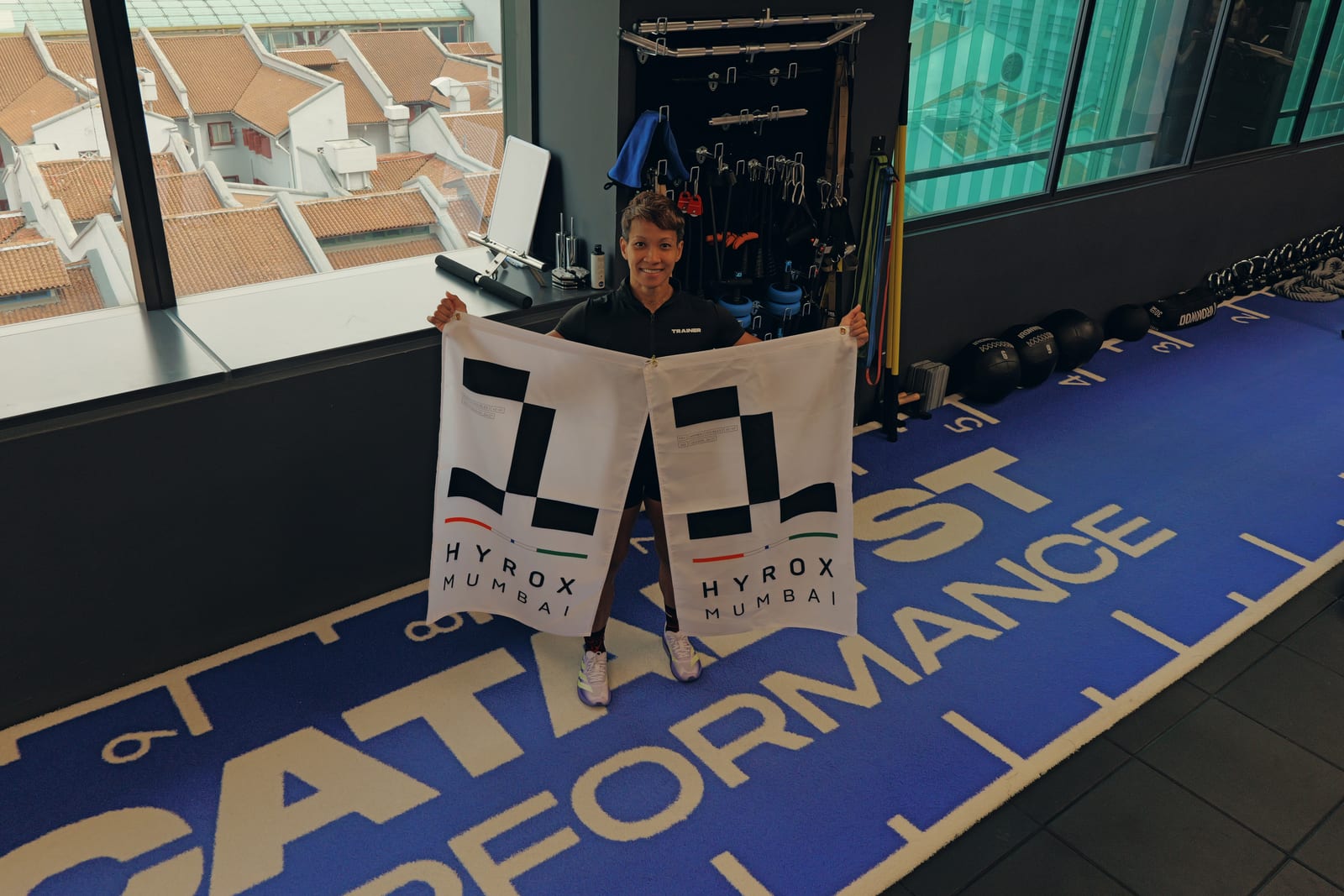Elly in the Catalyst Performance studio holding her two HYROX Mumbai first-place flags